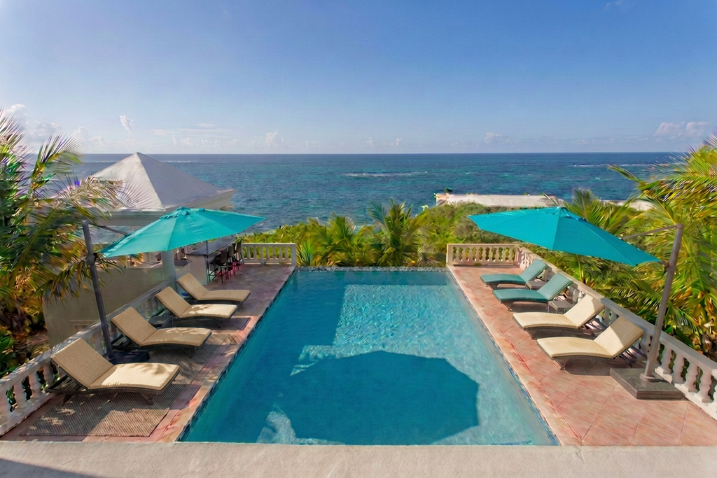Villa Amaaj's infinity pool deck with turquoise umbrellas and aquamarine loungers overlooking the Atlantic
